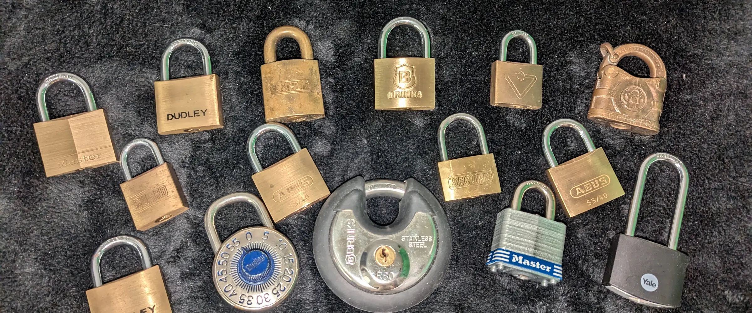 12 budget padlocks lined up on a workbench for testing